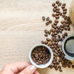 Flat lay of roasted coffee beans and portafilter on a wooden surface, showcasing coffee preparation.